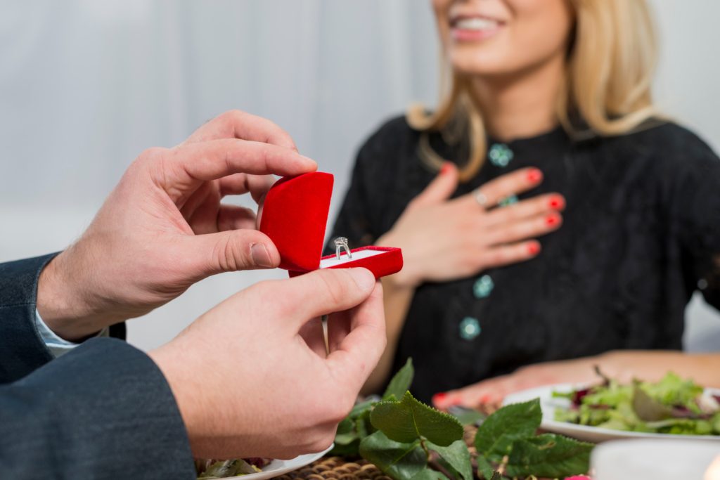 Jeweler measuring a woman’s finger for an engagement ring using a ring sizer